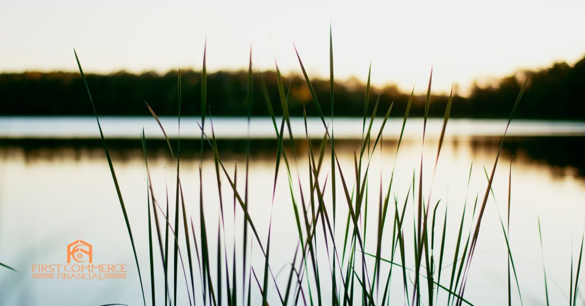 Sunset over a calm Michigan lake with tall reeds in the foreground — First Commerce Financial, Michigan second home and vacation property mortgage broker